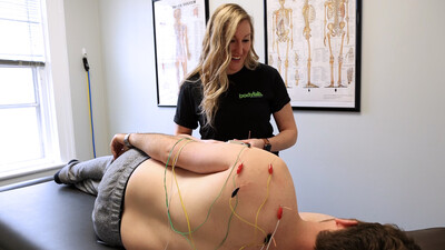 Registered physiotherapist doing electro-acupuncture on patient sidelying