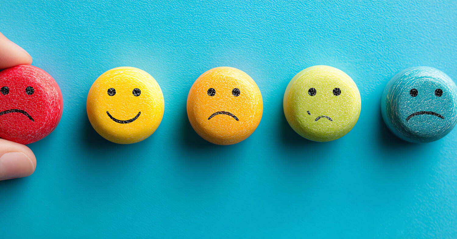Blue background, circle smiley faces along the middle different colours, most sad one happy face